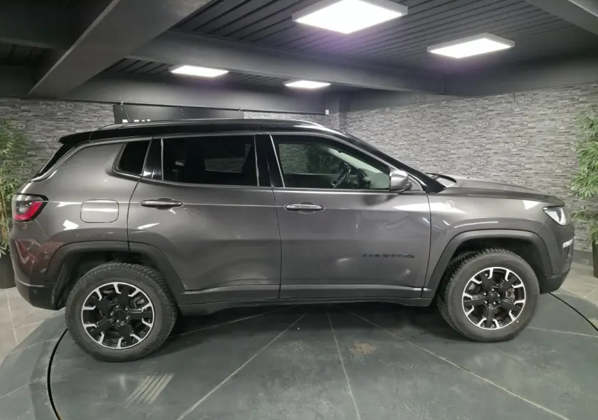 Jeep Compass gris foncé vu de profil côté gauche, avec jantes alliage noires et toit noir contrasté.