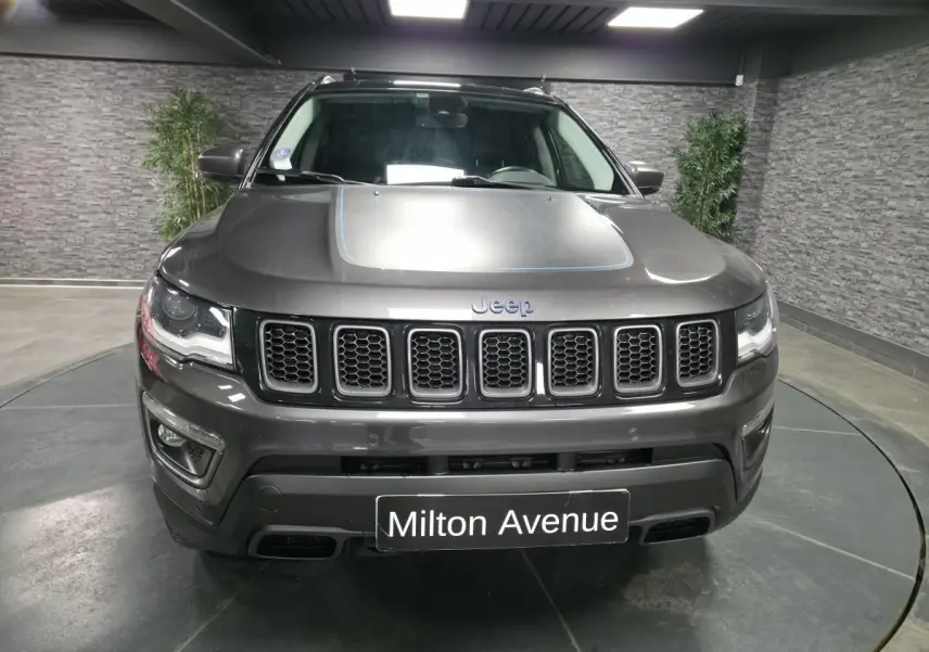 Vue avant d'un Jeep Compass gris foncé avec calandre à sept fentes et capot orné d'un liseré bleu.