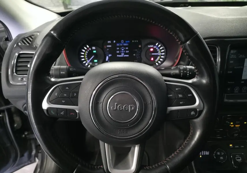 Volant cuir noir Jeep en gros plan avec commandes intégrées, tableau de bord numérique et écran tactile visible à droite