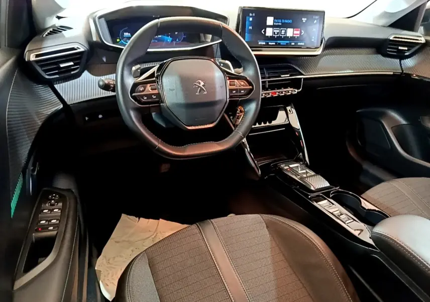 Vue intérieure avant de la Peugeot 208 2023, tableau de bord moderne avec écran tactile et volant cuir multifonctions.
