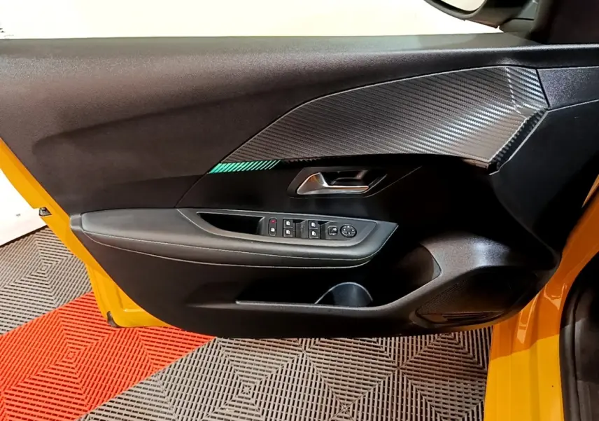 Vue rapprochée de la porte avant gauche jaune de la Peugeot 208 2023 avec garniture noire et inserts effet carbone.