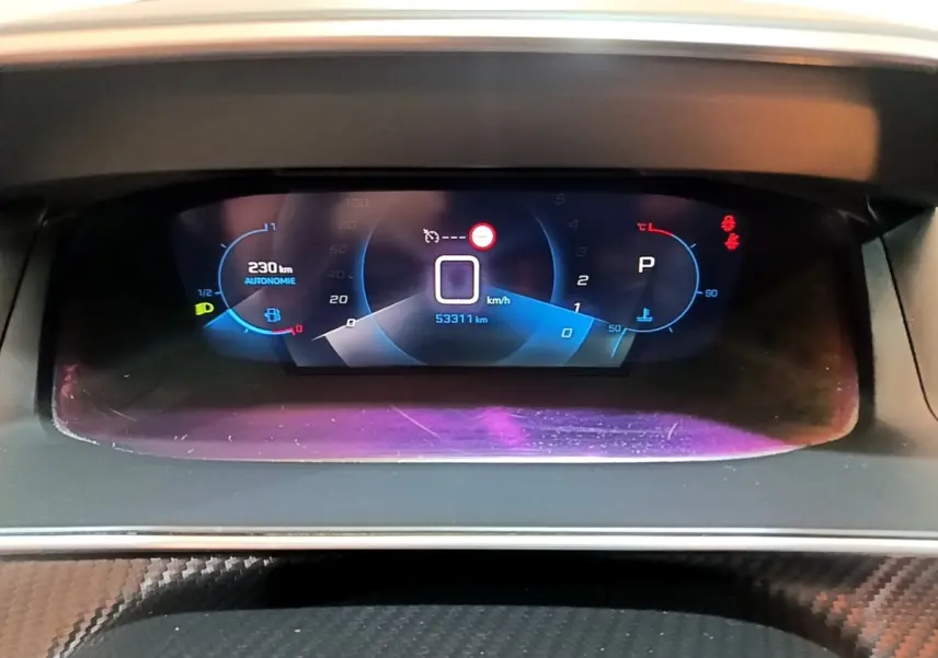 Tableau de bord numérique de Peugeot 208 jaune, affichage de la vitesse, autonomie et température moteur.
