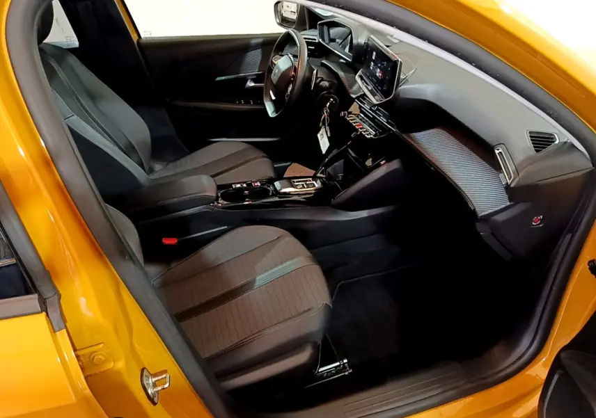 Vue intérieure côté conducteur de la Peugeot 208 jaune 2023, avec tableau de bord numérique et sièges noirs.