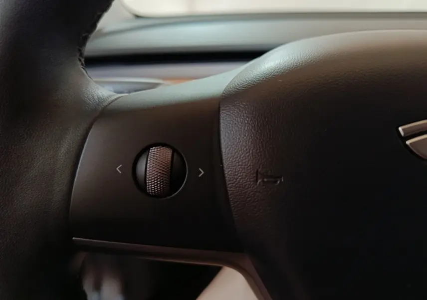 Gros plan sur la molette de commande sur le volant noir d'une Tesla Model 3 Grande Autonomie 2022.