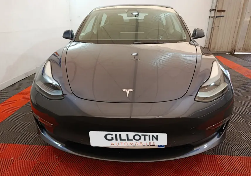 Vue avant d'une Tesla Model 3 gris foncé 2022, avec phares LED et logo Tesla visible sur le capot.