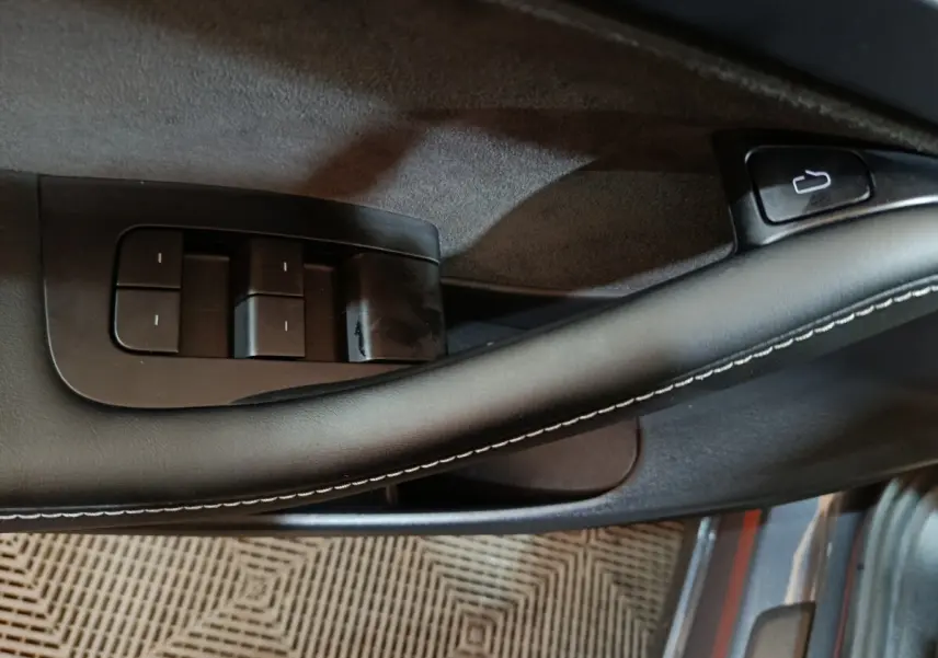 Détail de la commande des vitres sur la porte côté conducteur d’une Tesla Model 3 gris foncé, finition 2022.