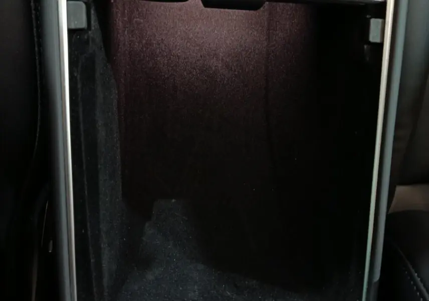 Intérieur du coffre central ouvert d'une Tesla Model 3 gris foncé, montrant un espace de rangement noir profond.