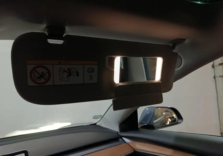 Détail du pare-soleil avec miroir éclairé côté conducteur dans l'habitacle d'une Tesla Model 3 gris foncé.