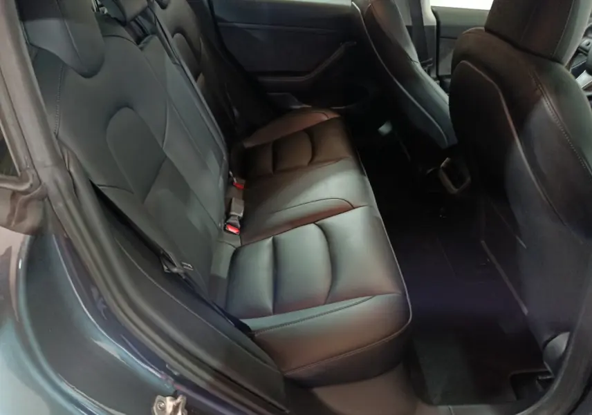 Vue intérieure côté arrière gauche montrant la banquette en cuir noir de la Tesla Model 3 Grande Autonomie gris foncé.