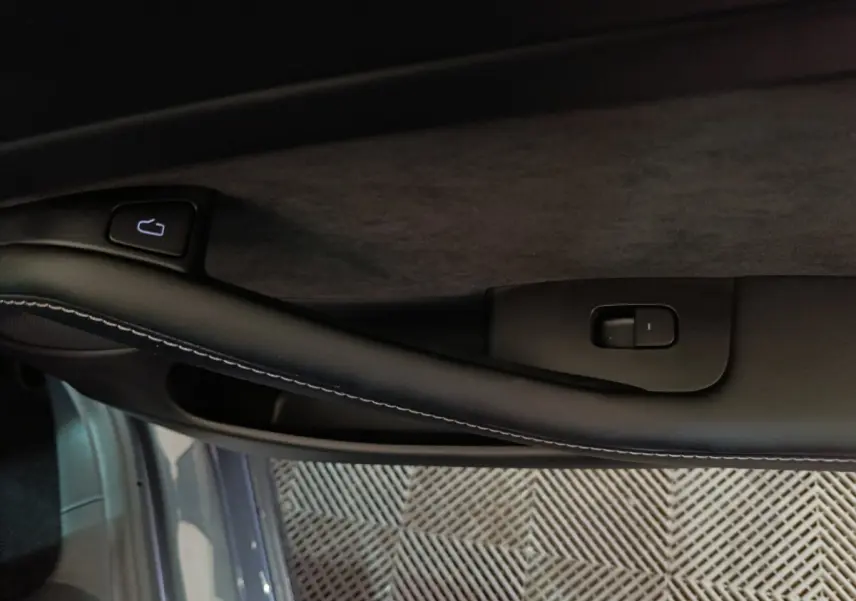 Gros plan sur la poignée intérieure côté gauche d’une Tesla Model 3 gris foncé avec bouton de verrouillage.