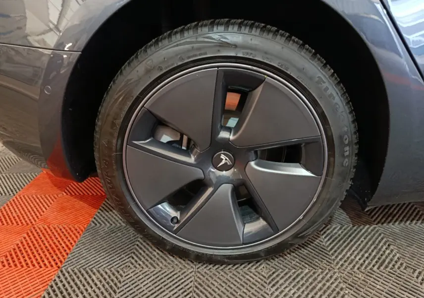 Vue rapprochée sur la roue arrière droite d'une Tesla Model 3 Grande Autonomie gris foncé de 2022.