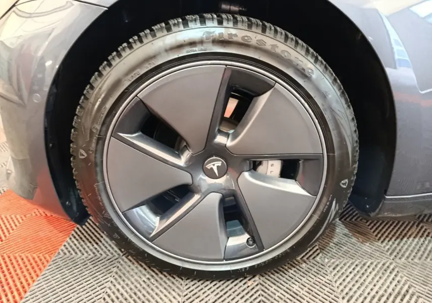 Gros plan sur la roue avant droite gris foncé d’une Tesla Model 3 Grande Autonomie 2022 avec jante aérodynamique.