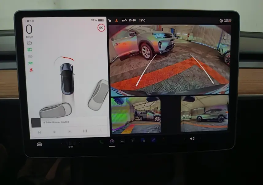 Écran central Tesla Model 3 2022 montrant caméra de recul et vues latérales d’un SUV gris en parking couvert.