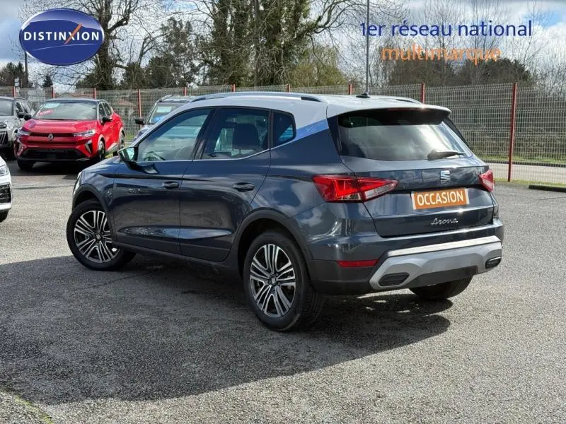 Vue 3/4 arrière droite du SEAT Arona 2025 bleu saphir avec toit blanc, soulignant ses feux arrière et jantes alliage.