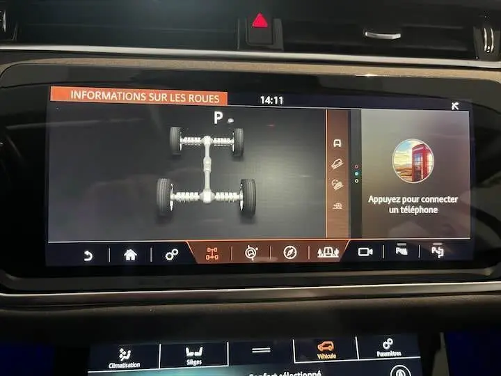Écran tactile du tableau de bord du Range Rover Evoque noir affichant les informations sur les roues et la connexion téléphone.