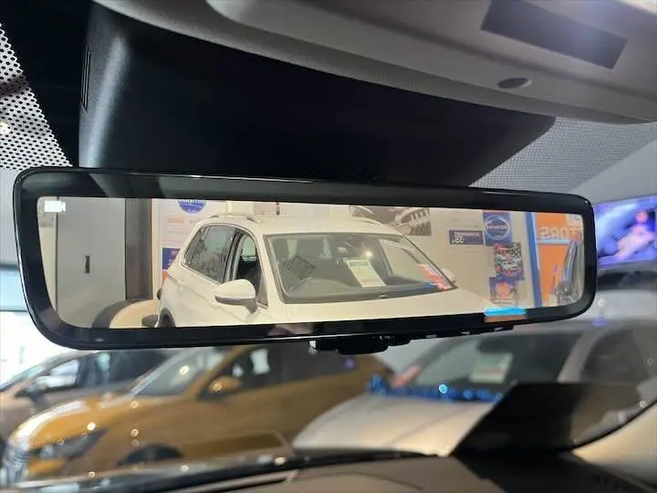 Reflet dans le rétroviseur intérieur montrant un SUV blanc en vue avant gauche dans un showroom.