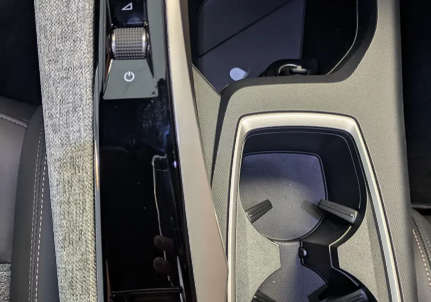 Vue plongeante sur la console centrale noire et beige du Peugeot 5008 blanc, avec porte-gobelets et commandes électroniques.