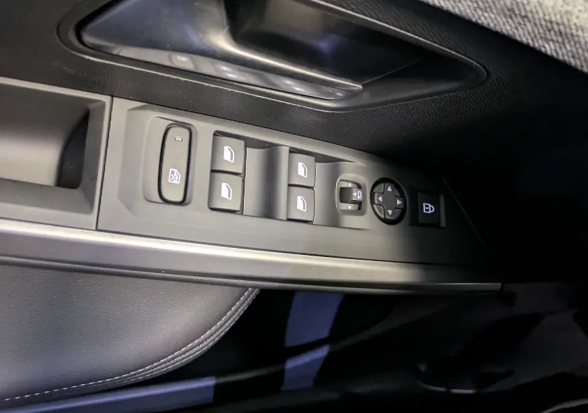 Vue rapprochée des commandes de lève-vitres et rétroviseurs sur la porte conducteur du Peugeot 5008 blanc Okenite 2025.