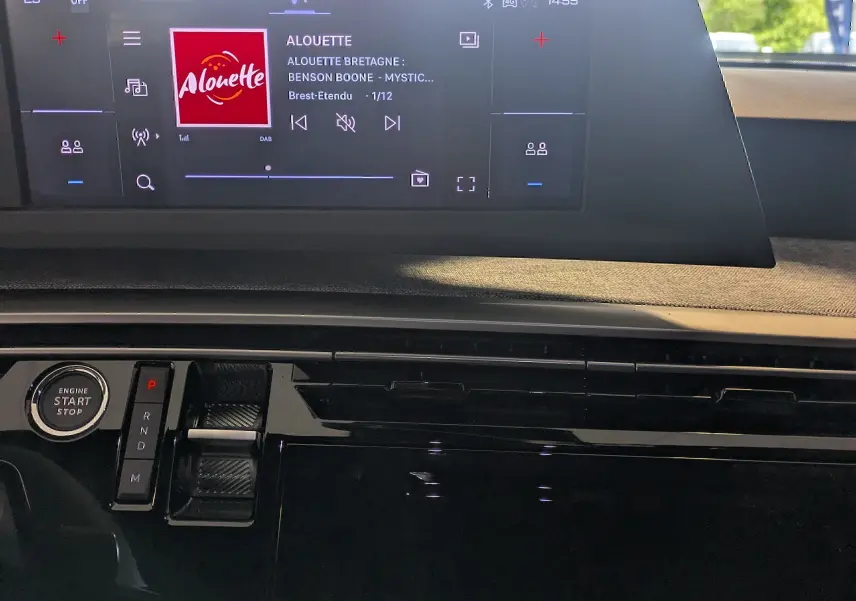 Vue intérieure du tableau de bord du Peugeot 5008 Hybrid 2025, avec écran tactile central et commande de boîte automatique.
