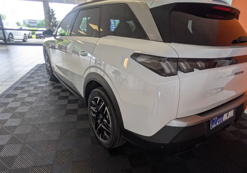 Vue 3/4 arrière droite d’un Peugeot 5008 blanc Okenite avec jantes alliage noires et vitres teintées.