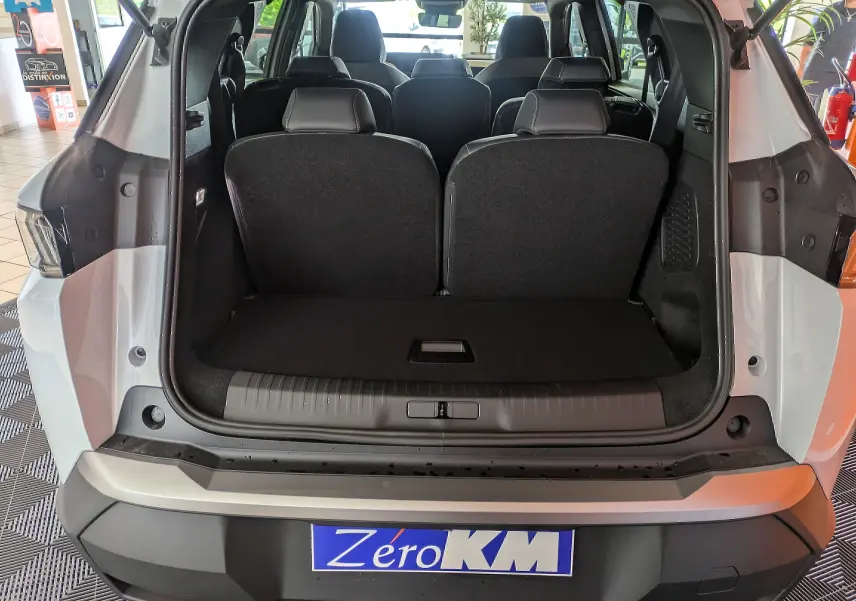 Coffre ouvert d’un Peugeot 5008 blanc Okenite, vue arrière montrant les sièges arrière et l’habitacle intérieur.