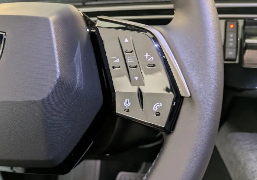 Gros plan sur le côté droit du volant noir du Peugeot 5008 2025, avec commandes vocales et téléphone intégrées.