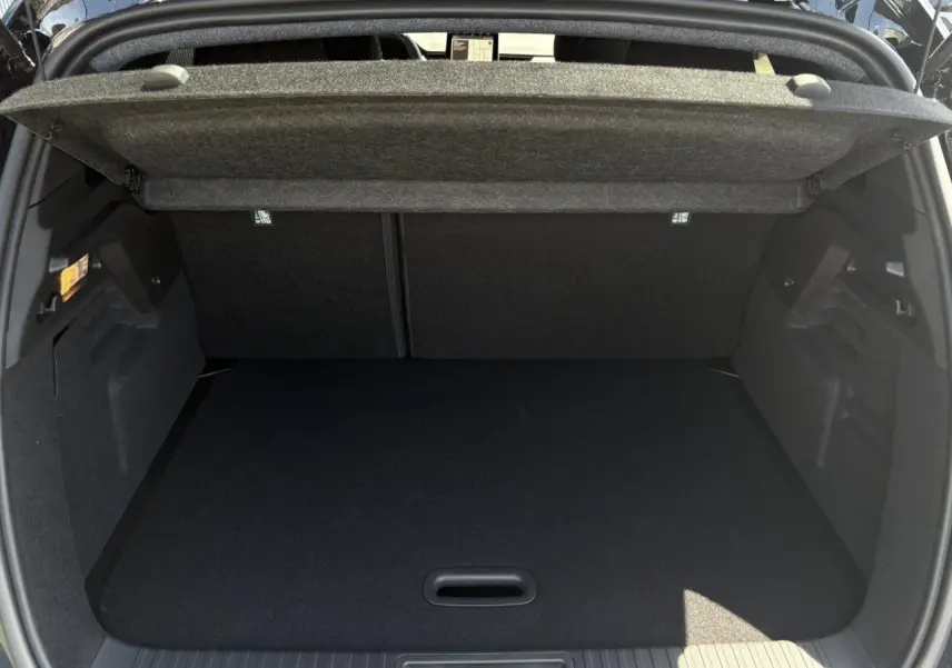 Coffre ouvert vu de l'arrière d'un Renault Captur noir étoile 2025, montrant un espace de rangement propre et spacieux.