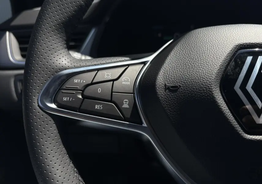 Gros plan sur le volant cuir multifonctions du Renault Captur noir étoile, mettant en valeur les commandes du régulateur adaptatif.