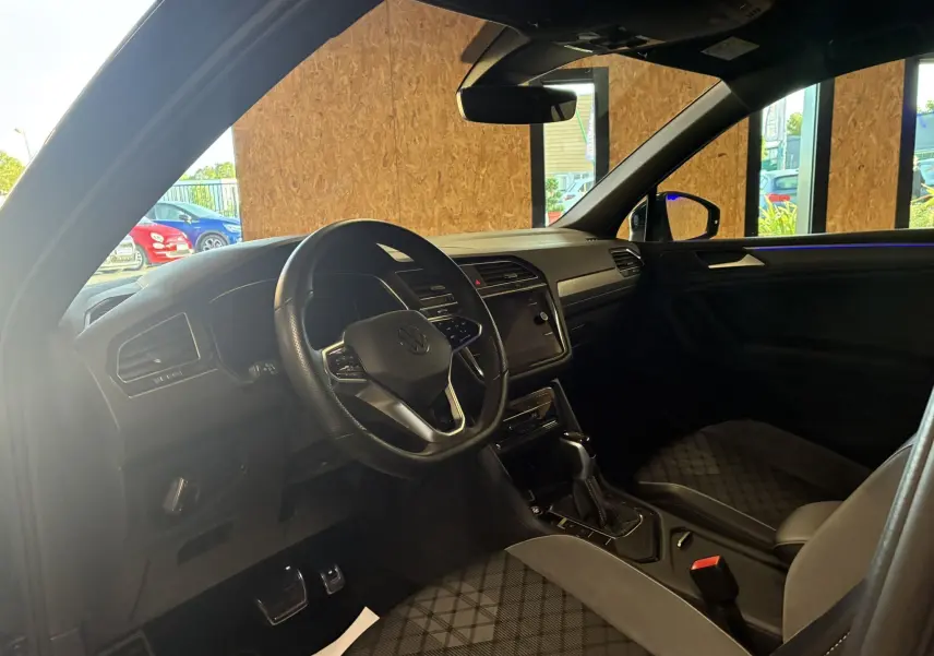 Intérieur noir du Volkswagen Tiguan 2022, vue côté conducteur, volant cuir multifonctions et sièges sport en tissu.