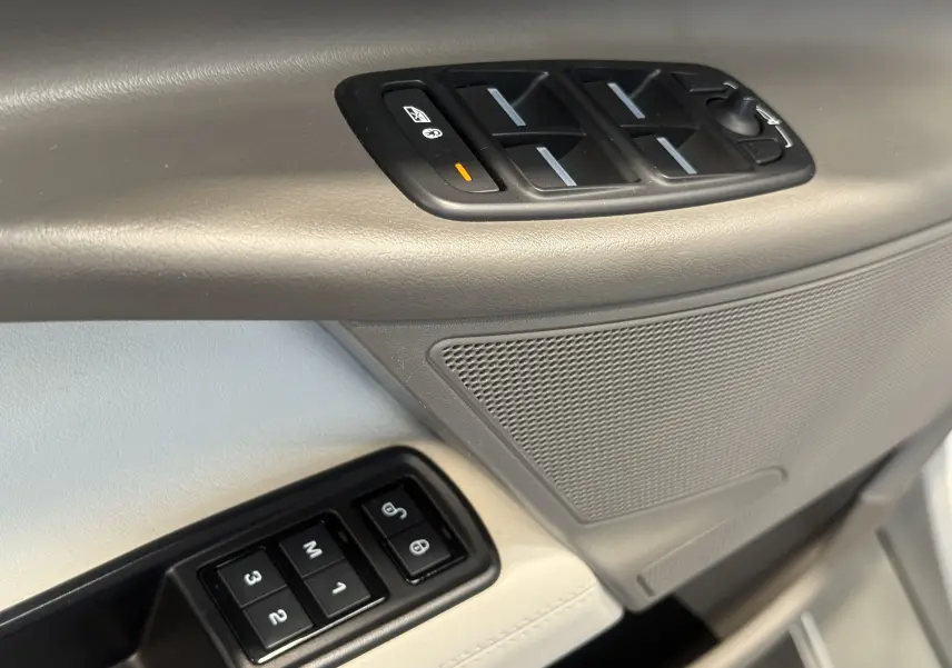 Gros plan sur la commande des vitres et la porte beige intérieur du Jaguar XE 20d Prestige 2015.