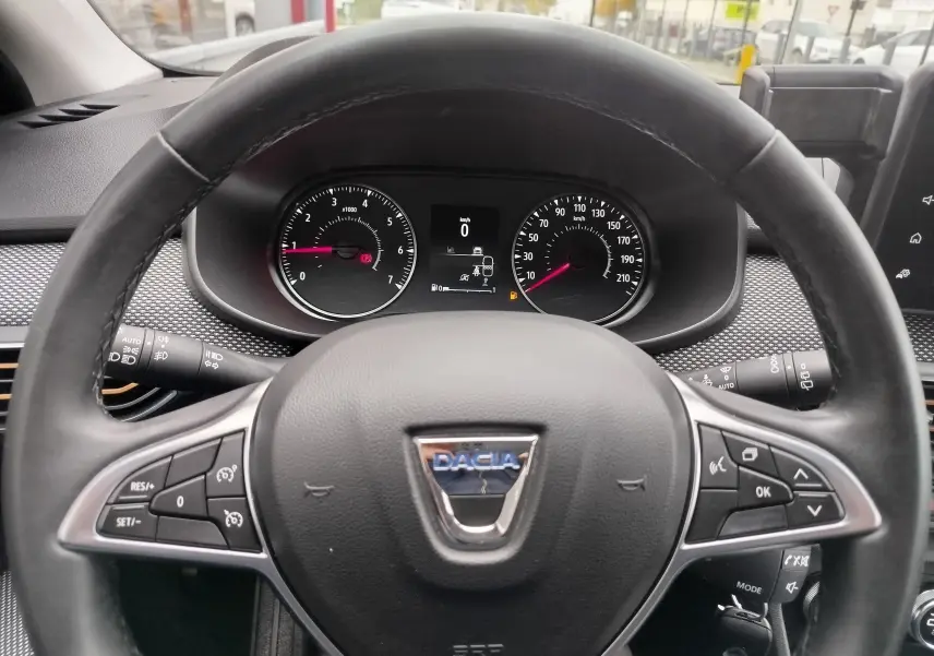 Vue rapprochée du volant noir de la Dacia Sandero Stepway 2021 avec commandes intégrées et tableau de bord digital.