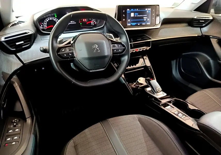 Vue intérieure avant centrée sur le volant cuir multifonctions et le tableau de bord numérique de la Peugeot 2008 gris foncé.