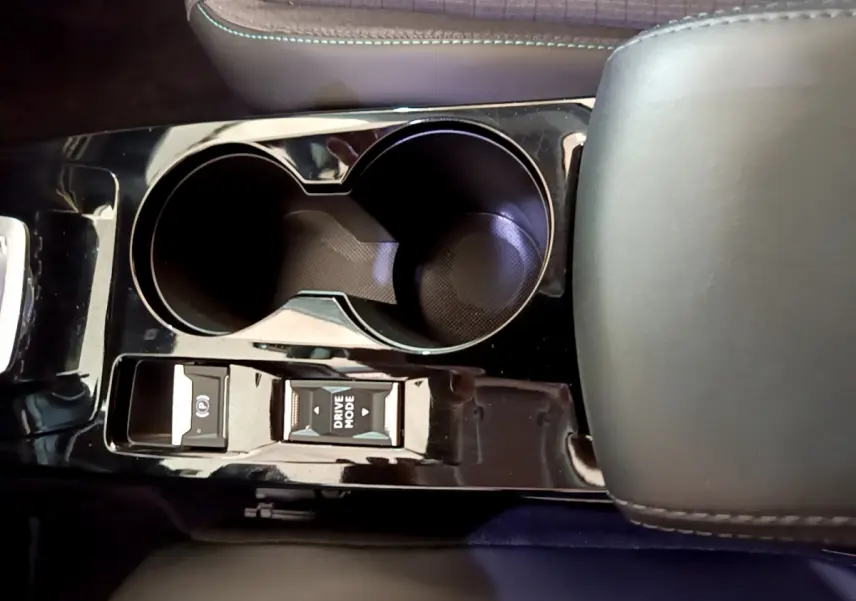 Gros plan sur la console centrale noire brillante du Peugeot 2008 avec porte-gobelets et commandes mode de conduite.