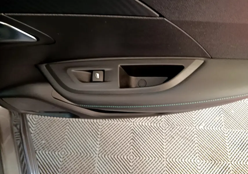 Gros plan sur la poignée intérieure et le bouton de lève-vitre côté gauche d’une Peugeot 2008 gris foncé, version 2022.
