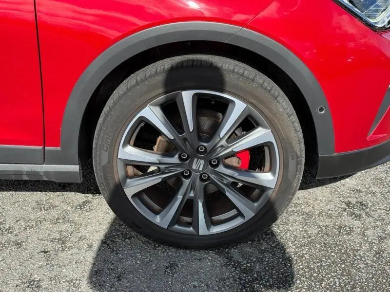 Gros plan sur la roue avant gauche d'une SEAT Arona rouge Désir avec jante alliage et étrier de frein rouge visible.