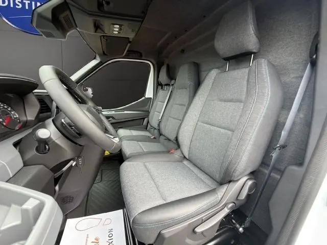 Vue intérieure côté conducteur du Renault Master blanc, montrant les sièges tissu gris et le volant réglable.