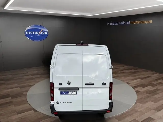 Vue arrière d’un utilitaire Renault Master blanc stationné en intérieur, portes arrière fermées, logo et badge visibles.