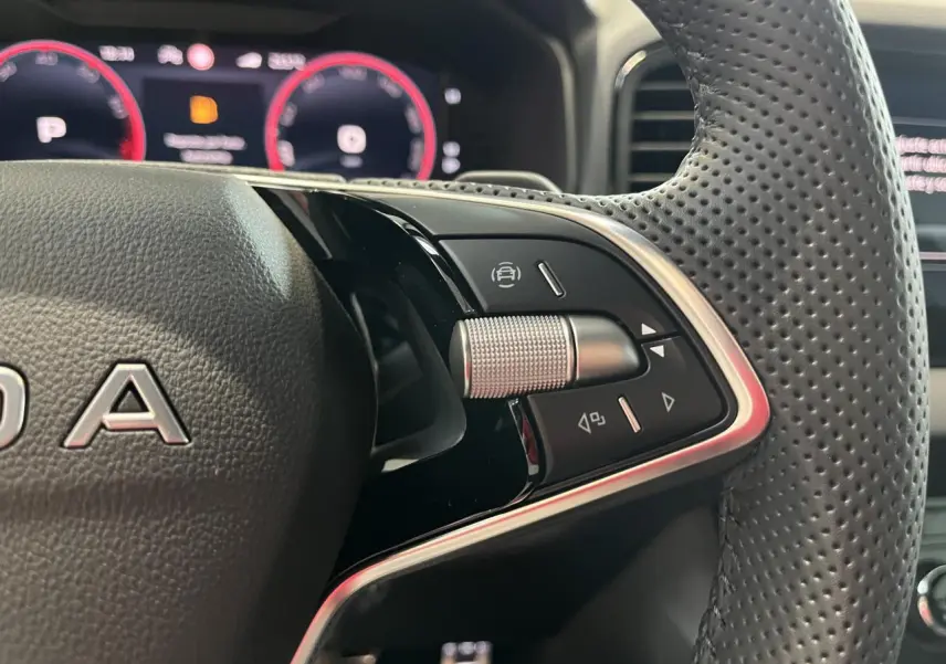 Gros plan sur les commandes à droite du volant cuir perforé du Skoda Karoq 2025, tableau de bord digital en arrière-plan.