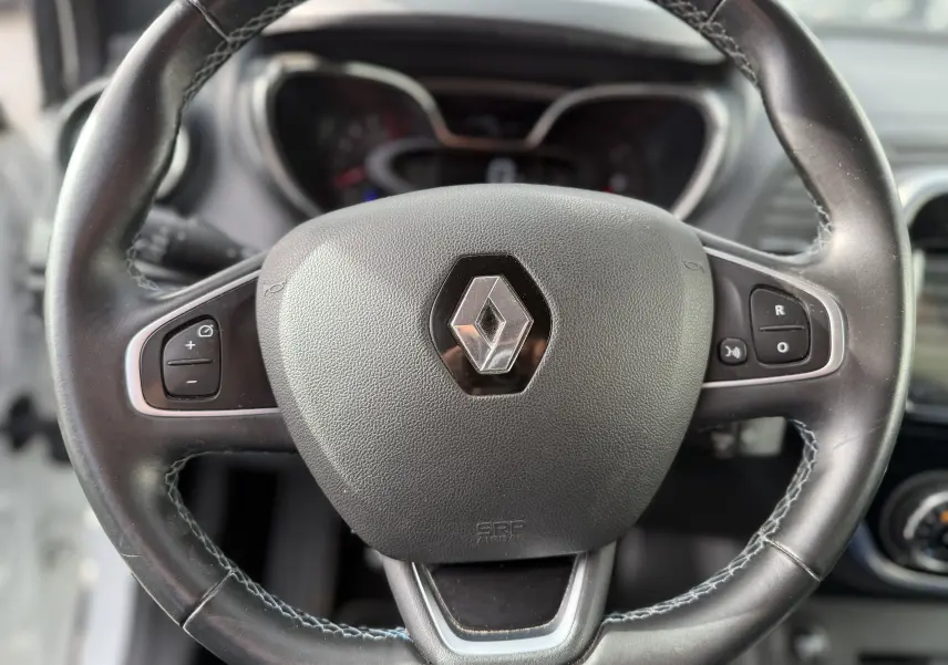 Gros plan sur le volant en cuir noir avec logo Renault au centre du Renault Captur blanc de 2017.