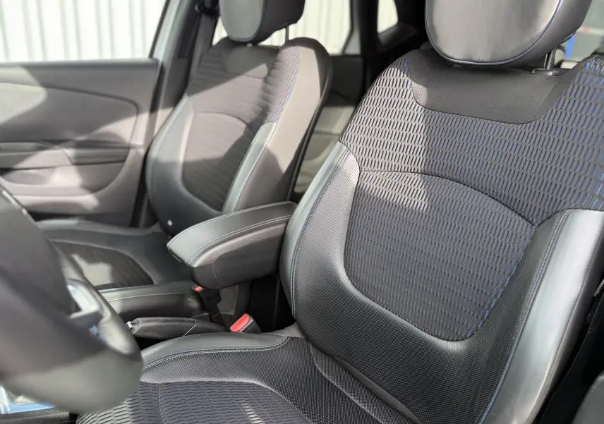 Gros plan sur les sièges avant noirs et bleus du Renault Captur 2017, avec accoudoir central et détails en cuir.
