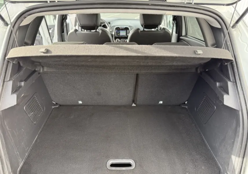 Coffre ouvert d'un Renault Captur blanc 2017, vue de l'arrière montrant l'espace de chargement et l'intérieur des sièges avant.