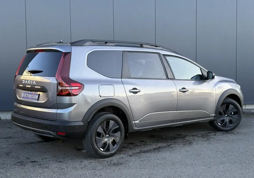 Vue 3/4 arrière droite du Dacia Jogger gris schiste avec barres de toit et jantes noires distinctives.