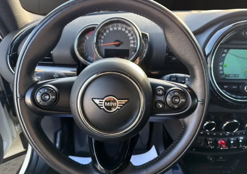 Vue centrée sur le volant cuir noir de la MINI Clubman F54 avec tableau de bord et écran tactile en arrière-plan.