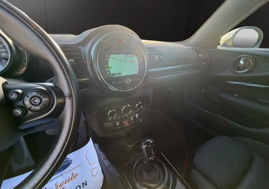 Vue intérieure côté conducteur du tableau de bord noir du MINI Clubman Cooper Exquisite avec écran tactile central allumé.