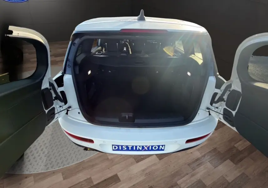 Vue arrière du coffre ouvert d'une MINI Clubman F54 blanche, montrant les portes battantes et l'espace de chargement vide.