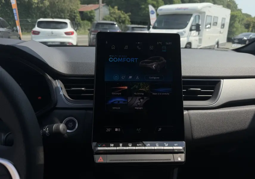 Vue intérieure centrée sur l’écran tactile vertical du tableau de bord du Renault Captur 1.8 E-Tech, ambiance noire.