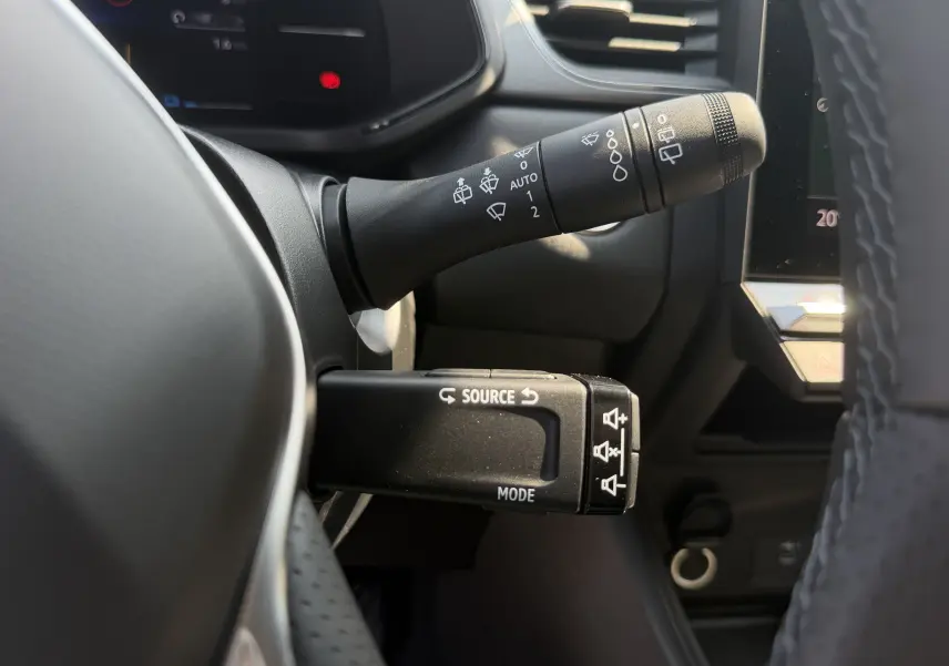 Gros plan sur les commandes au volant du Renault Captur 1.8 E-Tech gris Cassiopée, avec leviers de clignotants et multimédia.