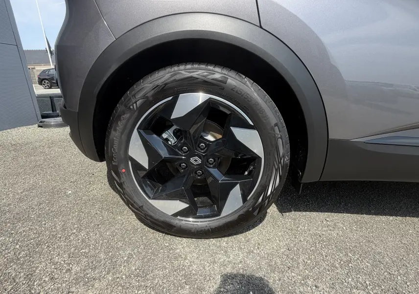 Gros plan sur la roue arrière droite du Renault Captur gris Cassiopée bi-ton avec jante aluminium 18 pouces au design étoilé.