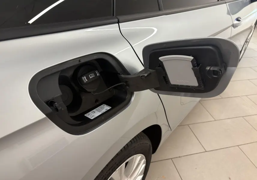 Vue rapprochée du côté gauche du Skoda Superb Combi gris argent, montrant la trappe de recharge hybride ouverte.