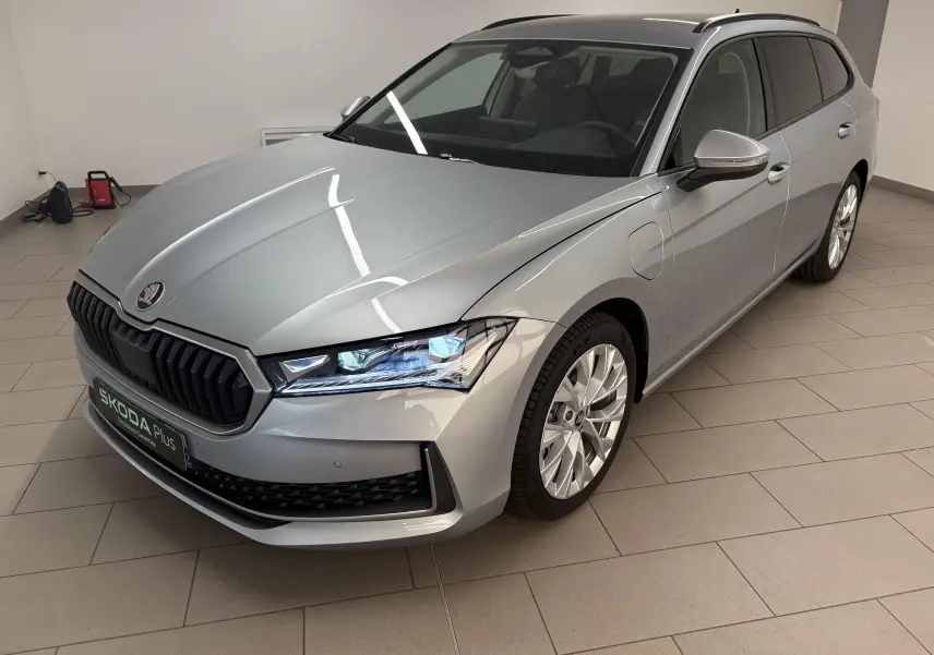 Vue 3/4 avant droite d'une Skoda Superb Combi gris argent avec jantes alliage 18 pouces dans un showroom.